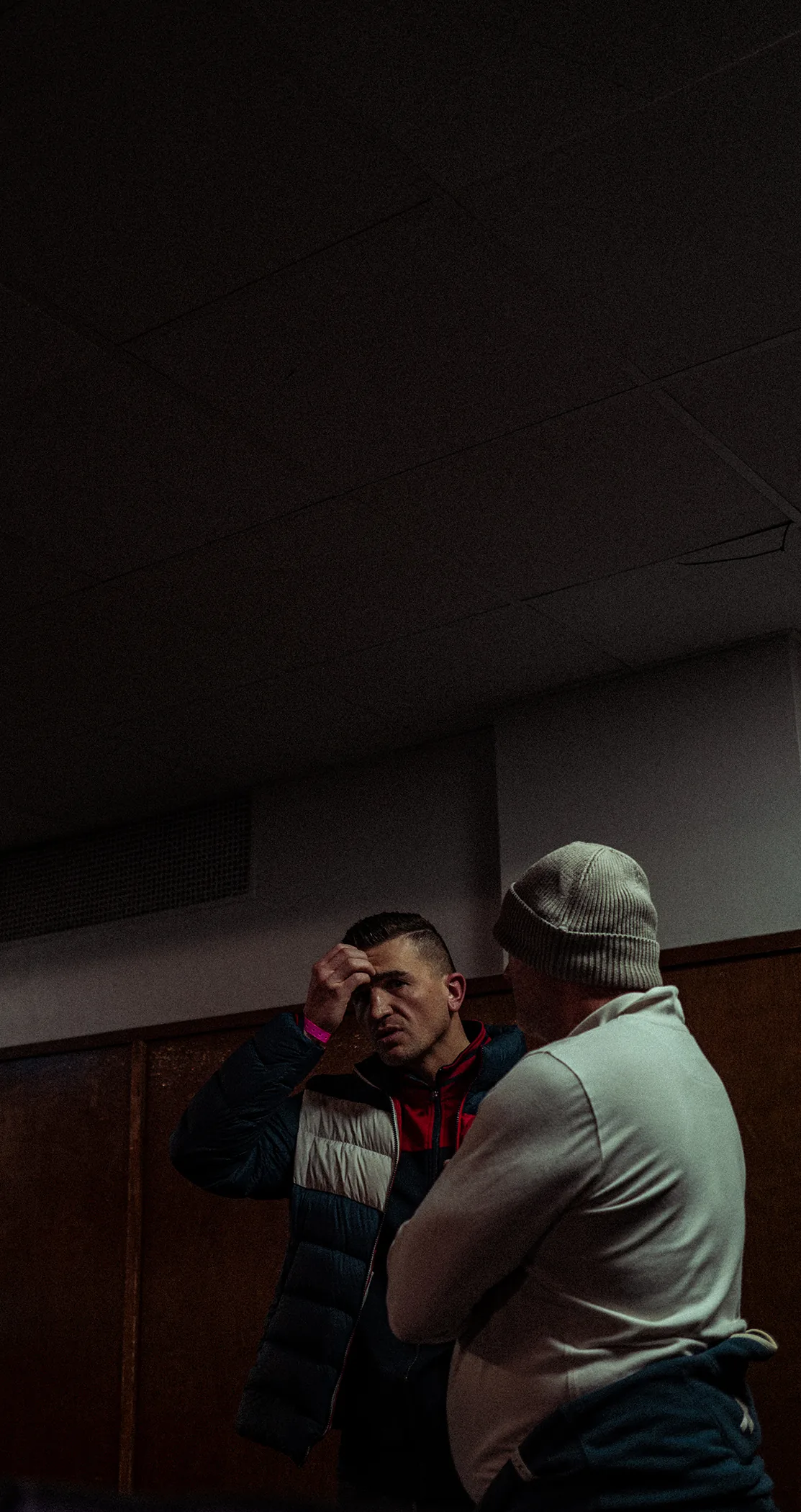 A trainer leaning in to a fighter in a dim changing room