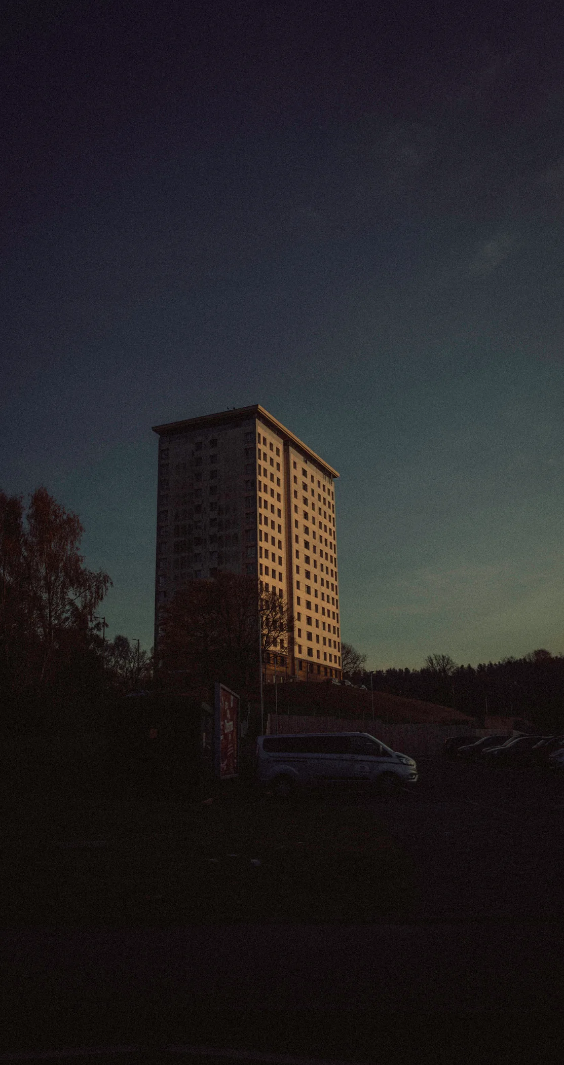 A lone tower block catching the last light at dusk