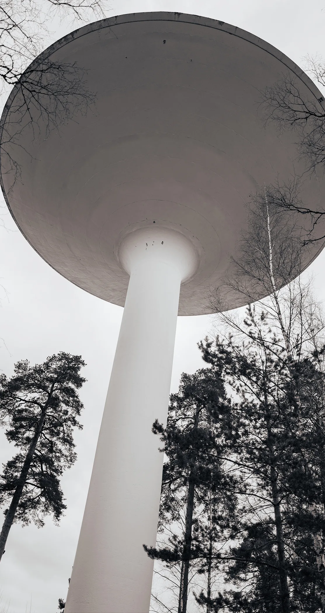 Looking up at a white water tower among bare trees, Sweden