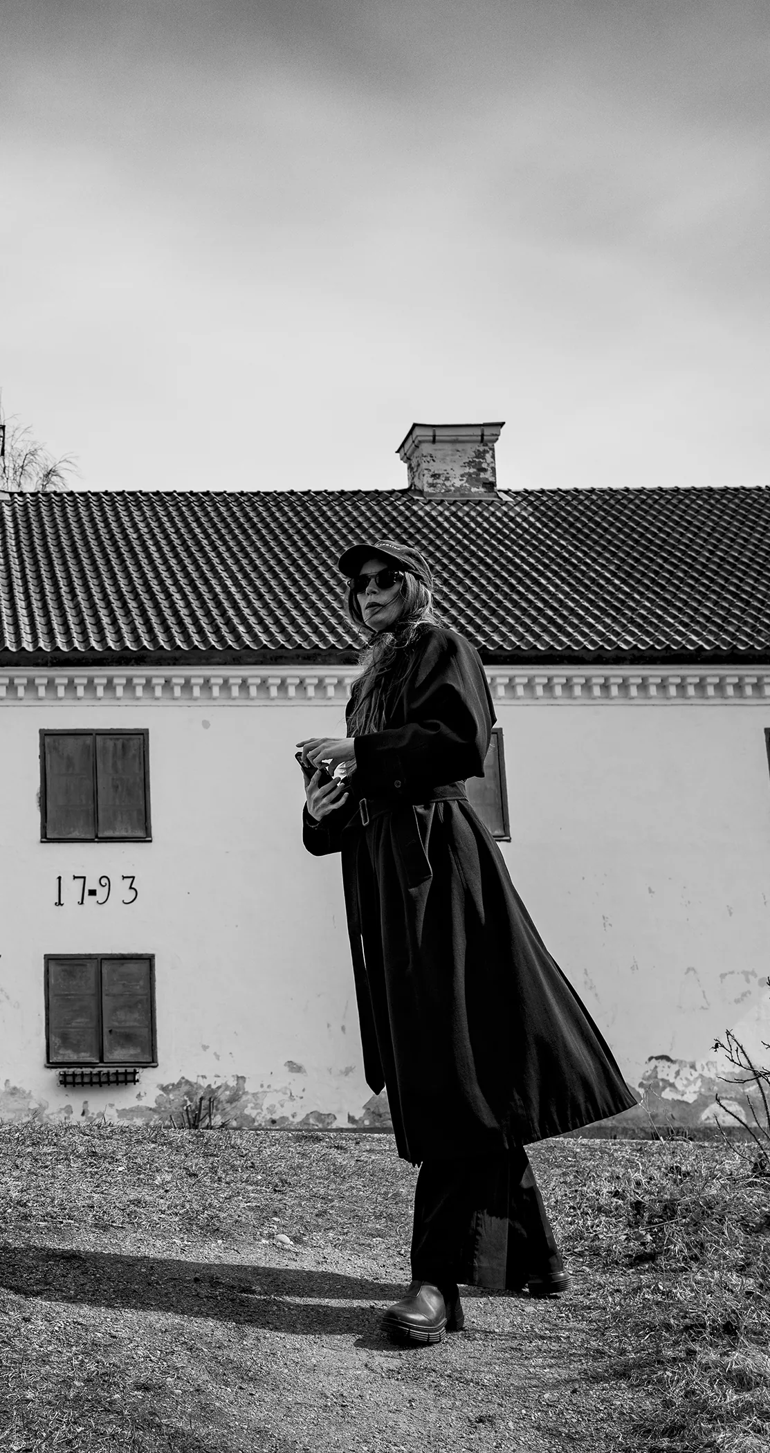 Figure in a long coat and flat cap before a manor dated 1793, Sweden